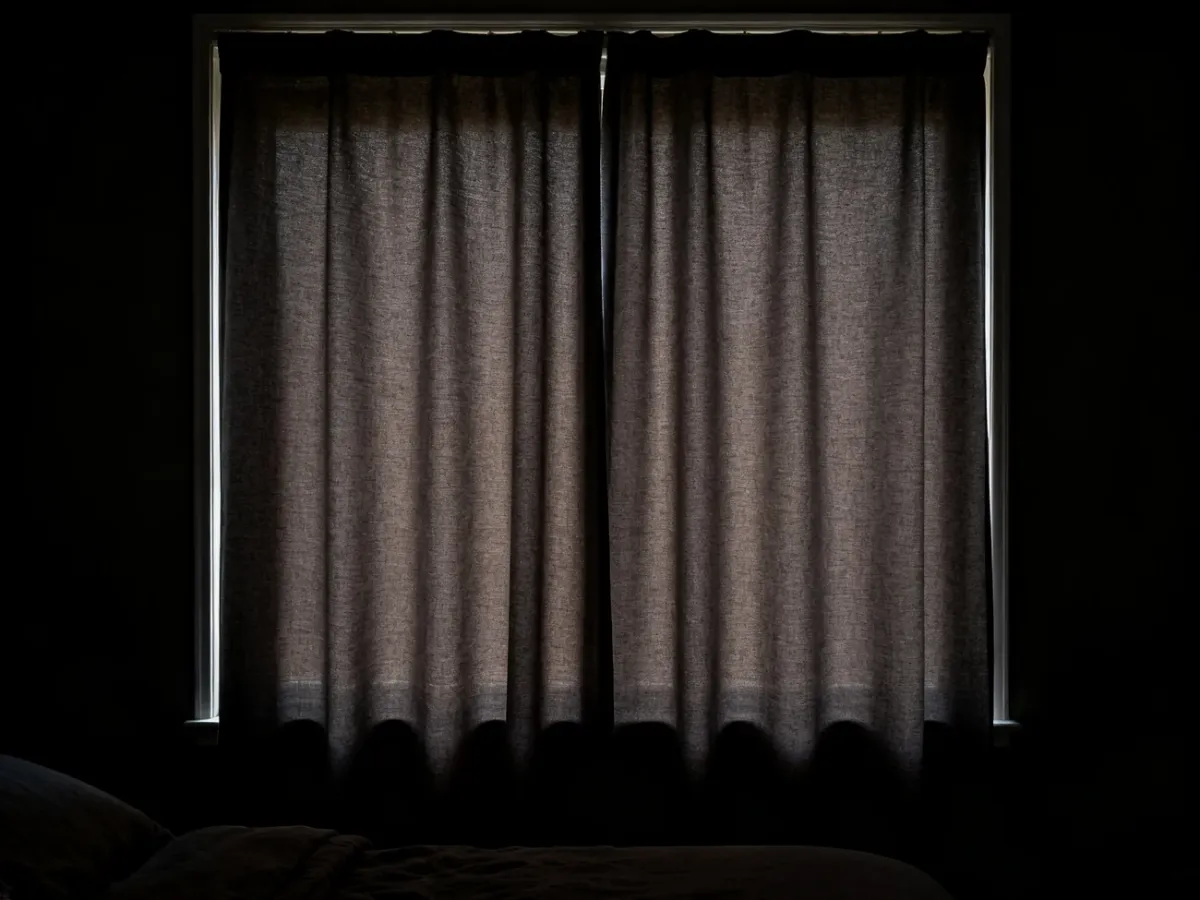Sypialnia z zasłonami blackout niemal całkowicie odcinającymi światło